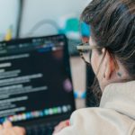 Woman with glasses coding on a laptop computer.