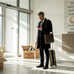 Professional with luggage entering Romanian office lobby